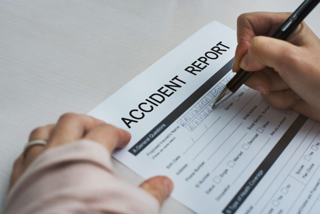 How to Settle or File an Auto Injury Lawsuit in Illinois blog image. Photo of a person filling out an auto accident report.