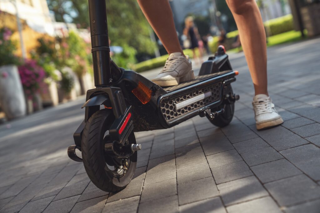Electric Scooters & The Law blog. Image of a person riding an escooter on a public walkway.